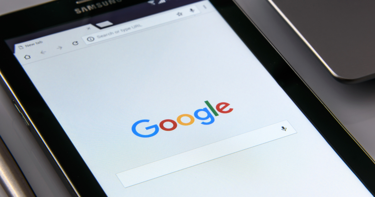 Close-up of a tablet screen displaying the Google homepage with focus on the search bar