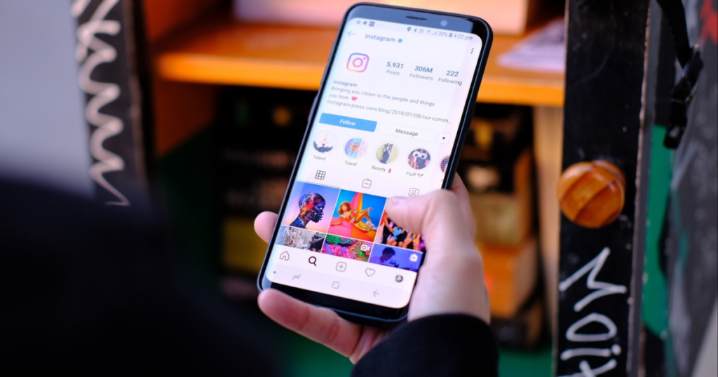 Instagram Reels, TikTok, and Facebook: Which Works Best for Your City? 1 Person browsing Facebook and Instagram feed on smartphone in a colorful urban setting