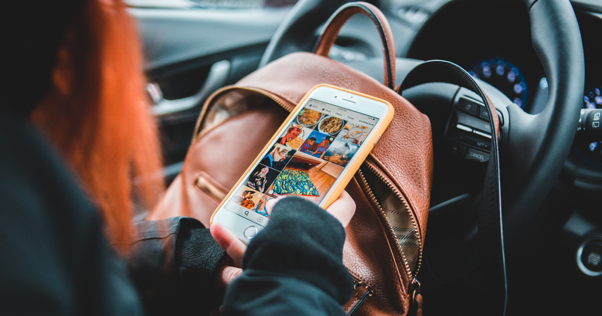 Person browsing social media on smartphone while sitting in car